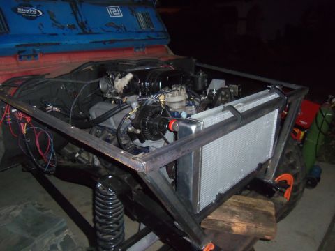 1968 Ford Bronco - Custom engine bay modification a large radiator and V8 engine, with a partial view of the vehicle's blue and red exterior.