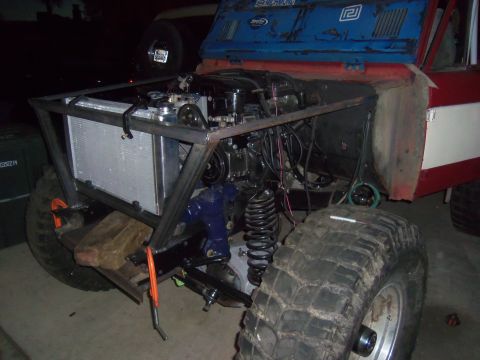 1968 Ford Bronco - The engine bay of a heavily modified off-road vehicle is shown with a custom roll cage and large tires.