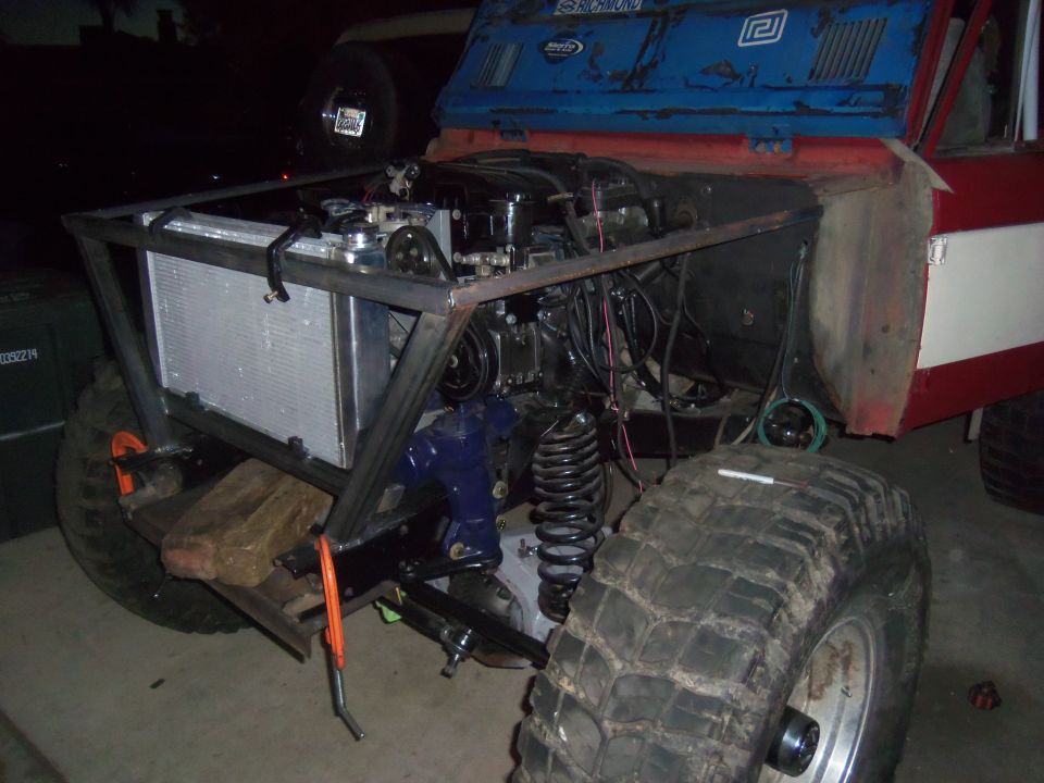 Custom off-road vehicle with engine exposed, large tires, and roll cage