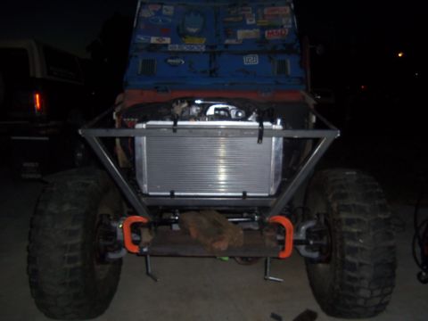 1968 Ford Bronco - An off-road vehicle is shown from the front, modified with a large radiator and roll cage, with another vehicle in the background.