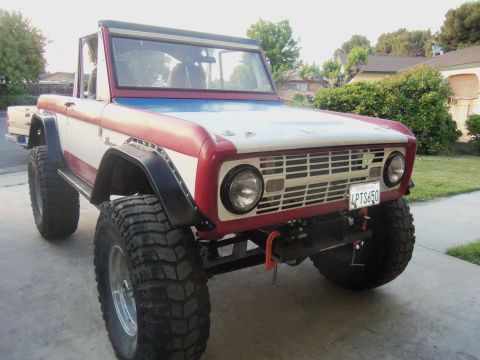 1968 Ford Bronco - This modified 1968 Ford Bronco features a red and white paint scheme and is equipped with oversized off-road tires and a front winch.