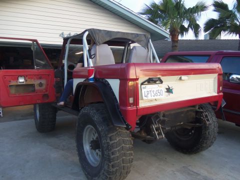 1968 Ford Bronco - Rear view of a lifted 1968 Ford Bronco with a two-tone red and white paint scheme and a soft top.