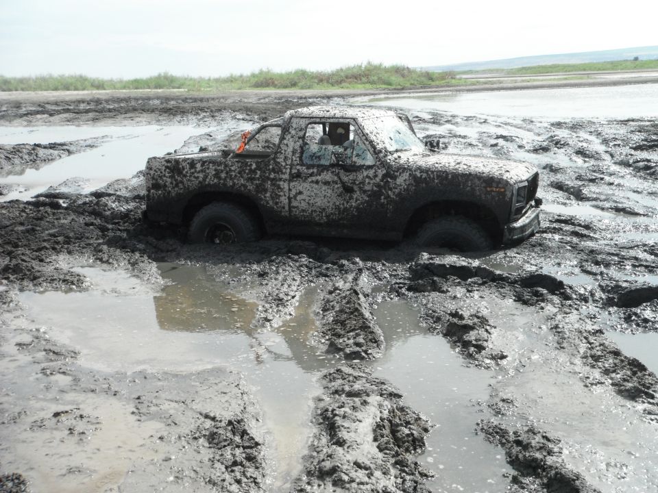 1980 Ford Bronco stuck deep in mud, front right wheel submerged