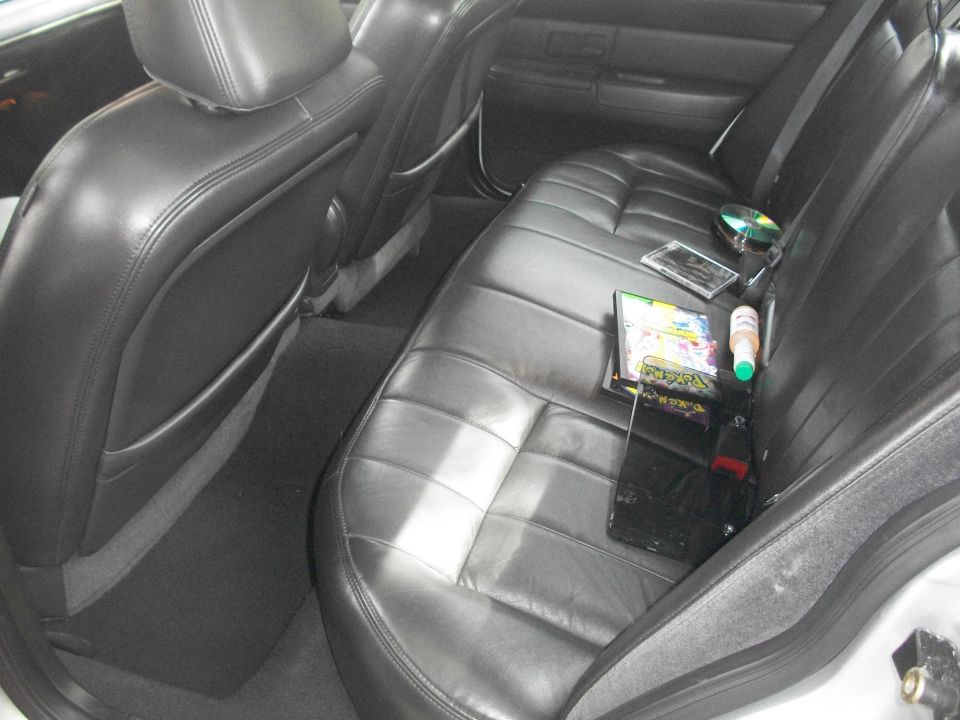 Rear leather seats of a 2003 Mercury Grand Marquis with CDs and a bottle on the seat