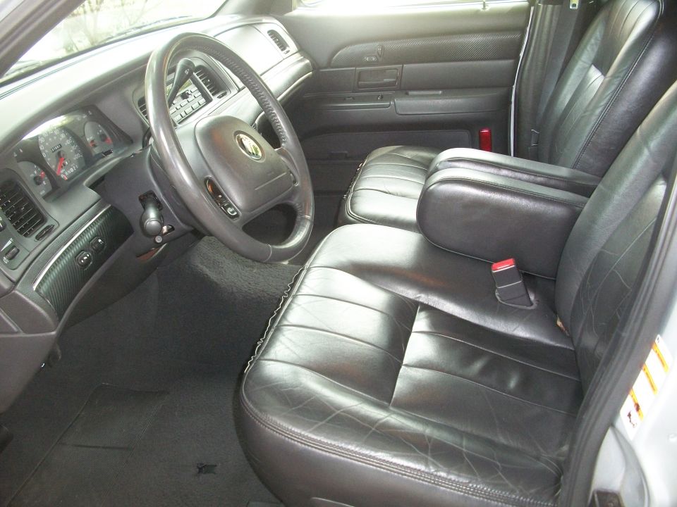 Interior shot of a 2003 Mercury Grand Marquis showing the driver's side dashboard, steering wheel, and front seats