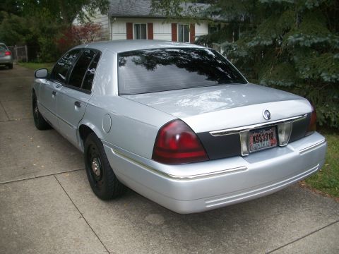 2003 Mercury Grand Marquis - Rear view of a silver 2003 Mercury Grand Marquis parked on a concrete driveway.