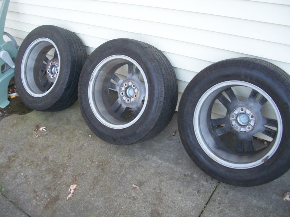 Three car wheels with tires leaning against a wall