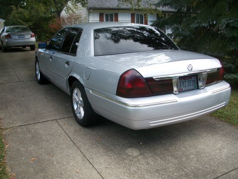 2003 Mercury Grand Marquis - A silver 2003 Mercury Grand Marquis sedan is parked on a concrete driveway, with another silver sedan visible in the background.