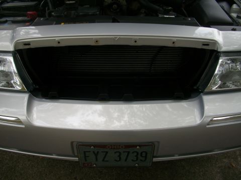 2003 Mercury Grand Marquis - Front view of a silver sedan, hood up, revealing the engine bay and grille.