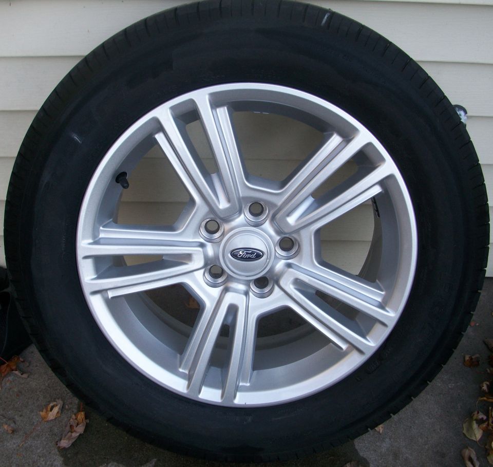 Ford wheel with silver spokes and a black tire. The Ford logo is in the center