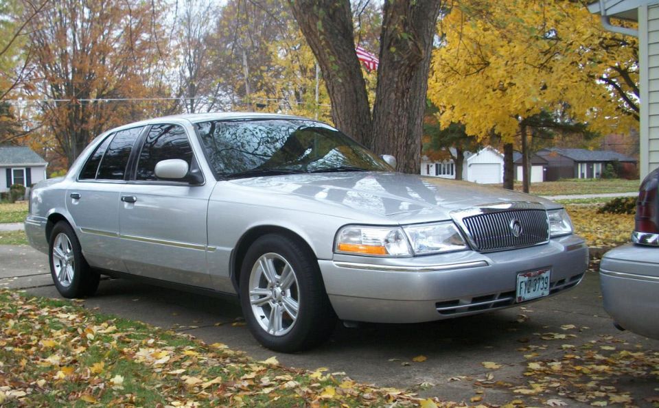 Silver 2003 Mercury Grand Marquis parked on a driveway with fall foliage