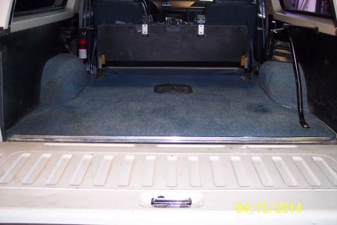 1990 Ford Bronco - The interior cargo area of a 1990 Ford Bronco shows blue carpet and a folded rear seat.