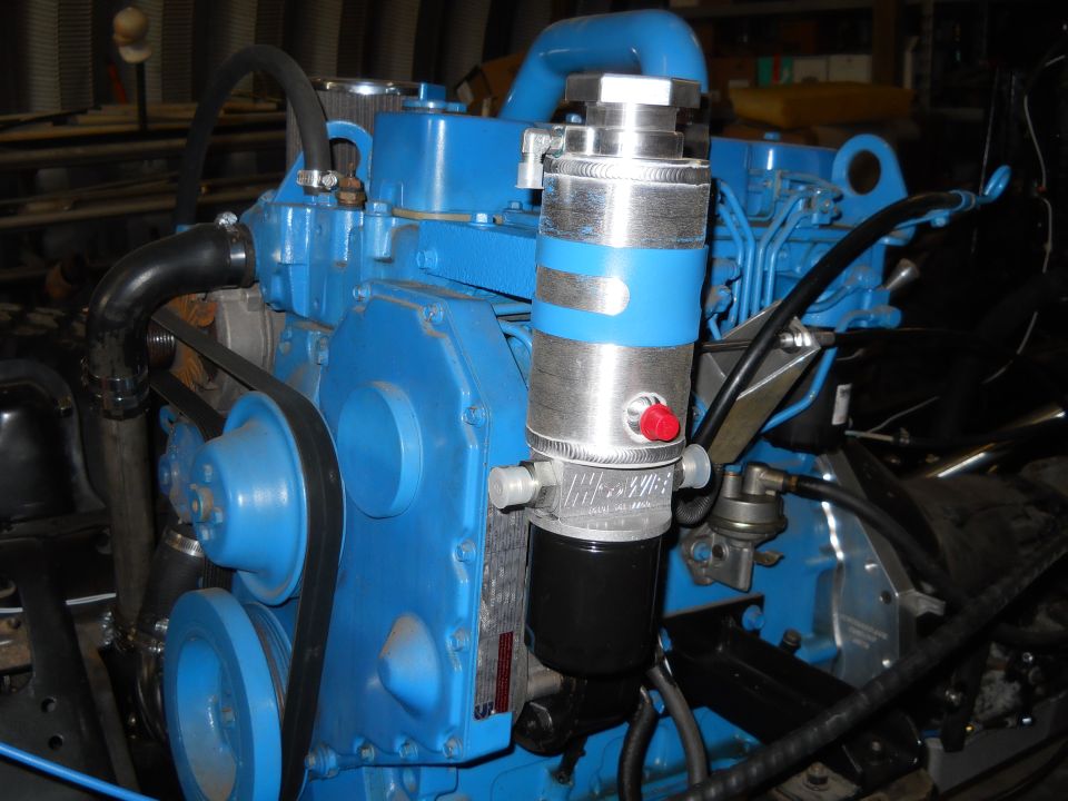 Blue engine block with silver and blue oil filter assembly and black hoses