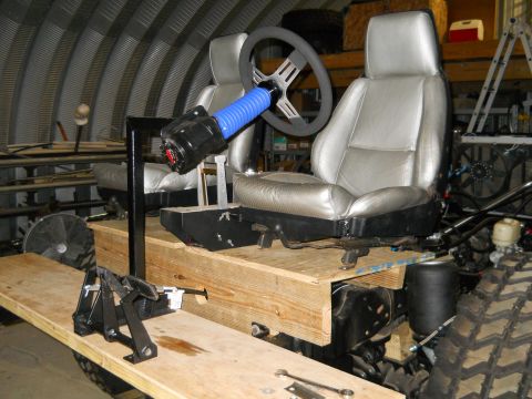 1992 Ford Bronco - This custom vehicle interior features two silver seats, a steering wheel, and a shifter mounted on a wooden platform.