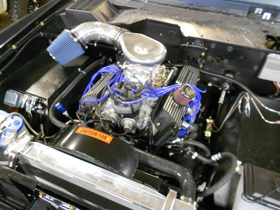 Engine bay with V8 engine, blue spark plug wires, and aftermarket air intake