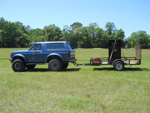 1992 Ford Bronco - Blue 1992 Ford Bronco with off-road tires tows a trailer loaded with a safe.