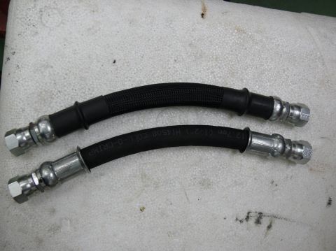 Two black rubber brake hoses with metal fittings. One hose has a braided sleeve