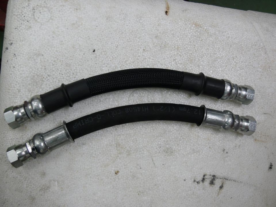 Two black rubber brake hoses with metal fittings. One hose has a braided sleeve