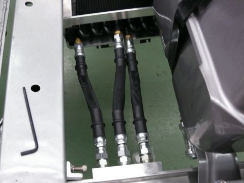 Brake lines connect to a radiator assembly. A hex wrench rests on a metal bracket