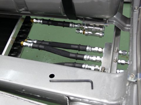 Close-up of braided hoses and metal fittings connected to a vehicle chassis