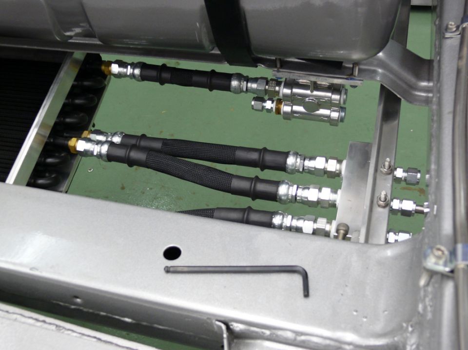 Close-up of braided hoses and metal fittings connected to a vehicle chassis