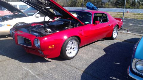 1972 Pontiac Trans Am - A shiny red muscle car is displayed with its hood up, revealing the engine bay.