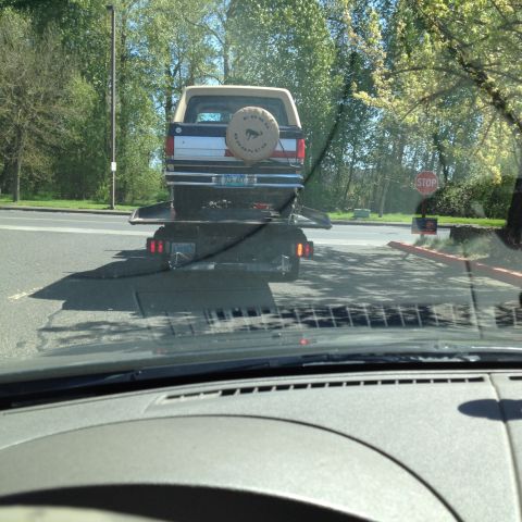 1990 Ford Bronco - A 1990 Ford Bronco is seen being transported on a trailer, with its distinctive spare tire cover visible.