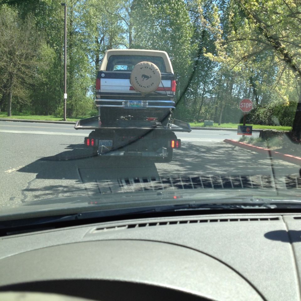 Rear view of a 1990 Ford Bronco on a trailer, showing spare tire cover