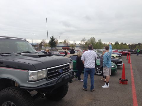1989 Ford Bronco - A lifted Ford F-Series truck is parked at an outdoor car gathering with other vehicles and people.
