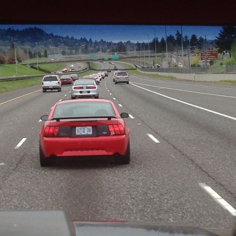 1989 Ford Bronco - Red Ford Mustang seen on the highway, other vehicles in traffic.