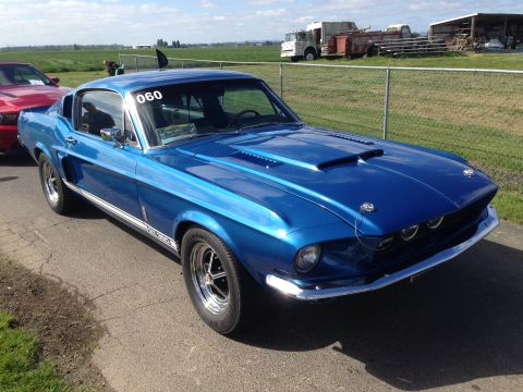 1989 Ford Bronco - A blue 1967 Ford Mustang Shelby GT500 is parked outdoors, with a red car visible to its left.