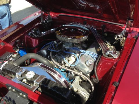 1989 Ford Bronco - The engine bay of a classic Ford Mustang, a V8 engine with blue spark plug wires and chrome detailing.