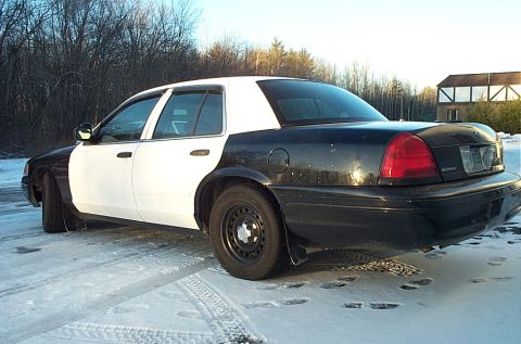 1991 Ford Crown Victoria LTD - Side view of a black and white police car on a snowy day.