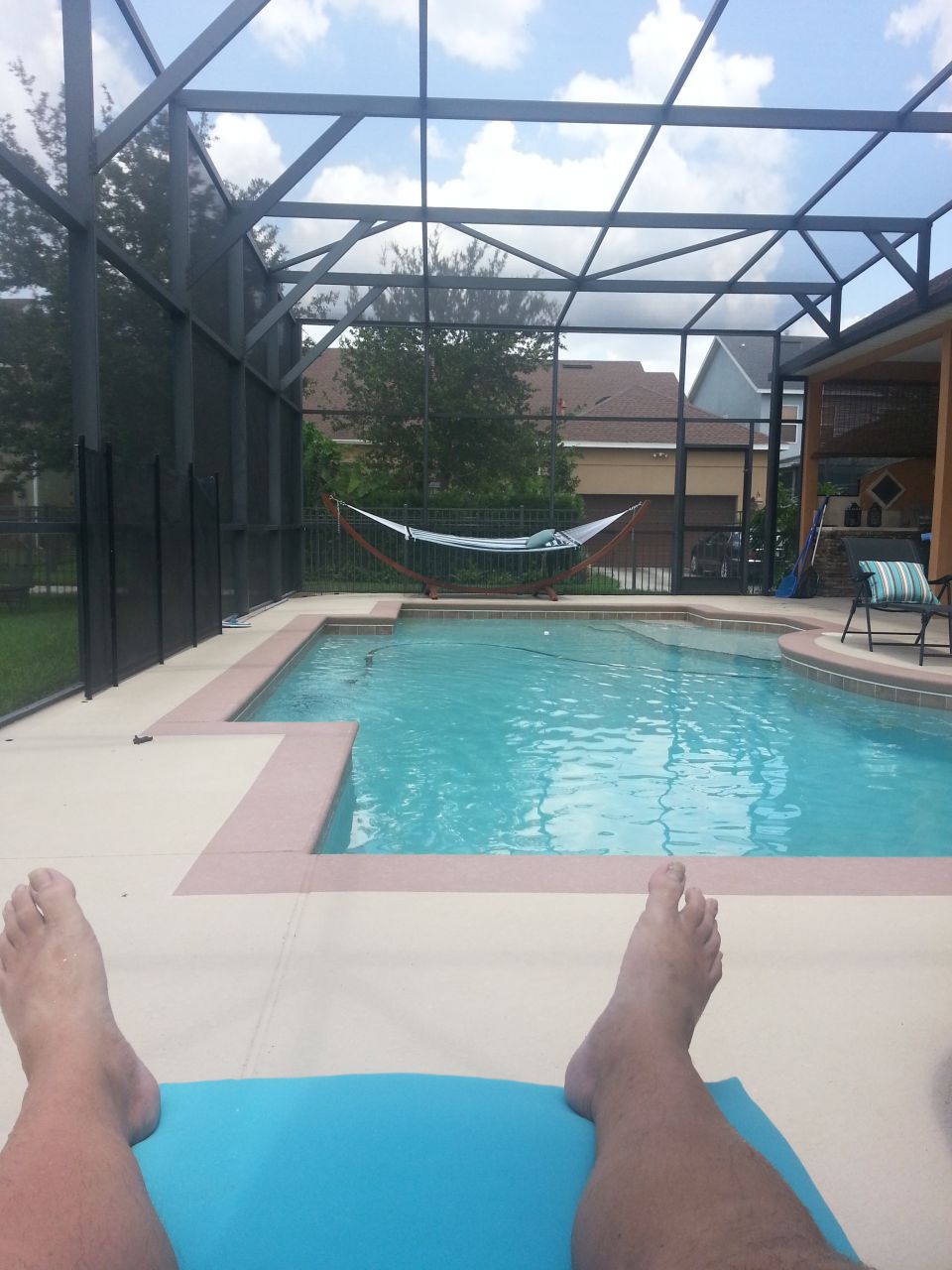Pool scene with hammock and lounge chair under screened enclosure