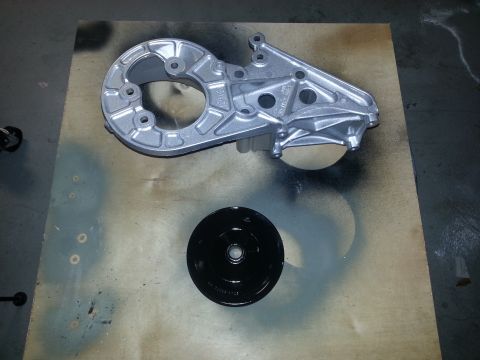 1994 Ford Bronco - Engine bracket and pulley, possibly for a Ford Bronco, are laid out on a surface.