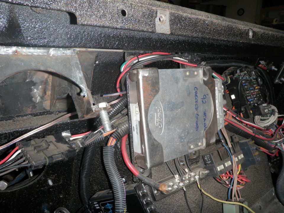 Vehicle's interior electrical system with a Ford-branded metal cover, fuse box, and wiring