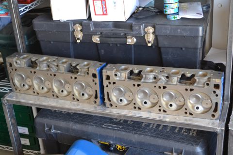 1981 Ford F-250 - A pair of engine cylinder heads are displayed on a metal shelf, with storage containers in the background.