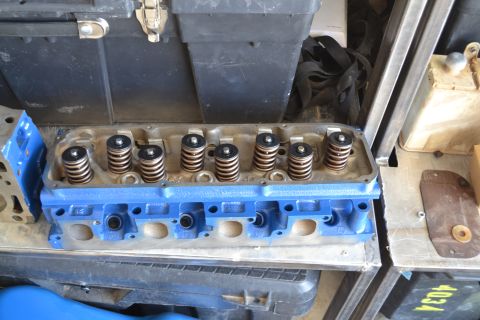 1981 Ford F-250 - A blue painted engine cylinder head with valve springs is shown, resting on a shelf.
