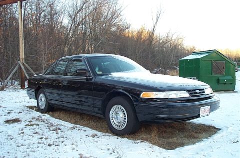 1991 Ford Crown Victoria LTD - A black 1991 Ford Crown Victoria LTD sedan is parked on a snowy lot with trees in the background.