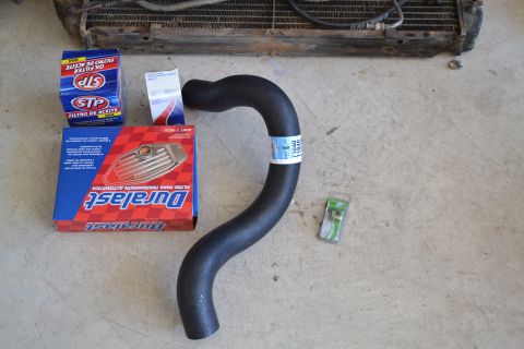 1981 Ford F-250 - Various automotive parts including a radiator, oil filter, transmission filter, and a hose are laid out on a concrete surface.