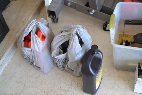 1981 Ford F-250 - A collection of automotive parts and fluids are organized on a garage floor.