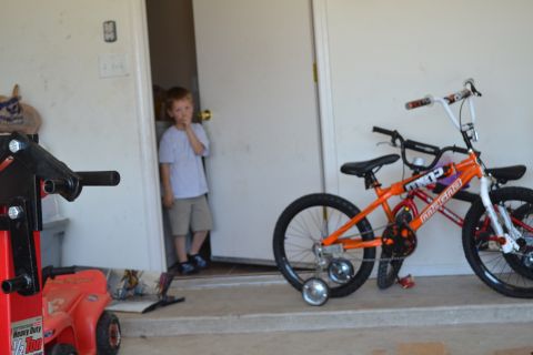 1981 Ford F-250 - A young boy stands in a doorway next to an orange bicycle equipped with training wheels.
