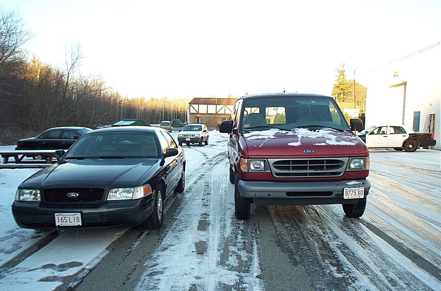 Black Ford Crown Victoria and red Ford Econoline van parked on a snowy road
