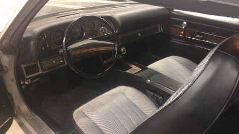 1976 Pontiac Trans Am - Interior view of a 1976 Pontiac Trans Am, patterned cloth seats and wood grain accents on the dashboard and door panels.