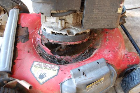 2006 Honda RANCHER - Damaged lawn mower deck with rust and a warning sticker visible.