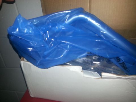 1994 Ford Bronco - A vehicle part is visible, wrapped in blue plastic and placed inside a cardboard box.