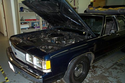 1991 Ford LTD Crown Victoria - The engine bay of a 1991 Ford Crown Victoria is visible with the hood raised.