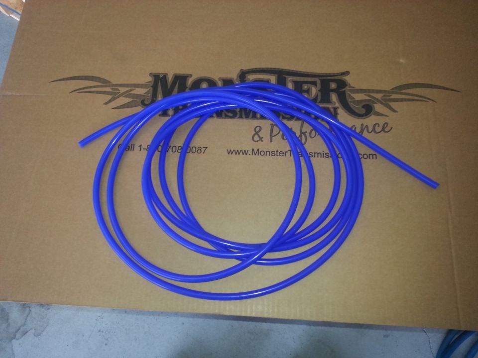 Blue tubing coiled on a cardboard box with "Monster Transmission & Performance" logo and website