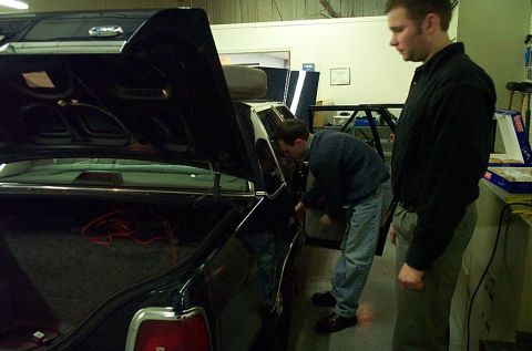 1991 Ford LTD Crown Victoria - Two men are seen working on the interior and trunk of a dark-colored vehicle in a garage setting.