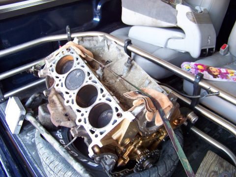 1999 Mercury Grand Marquis - Engine block with pistons visible, resting in the bed of a truck next to seats.